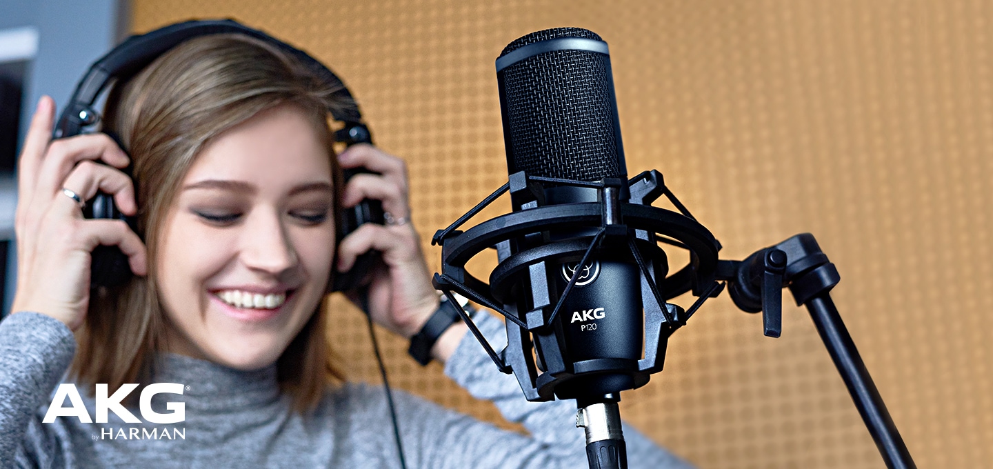 여성이 헤드셋을 착용하며 마이크 앞에 서있습니다.