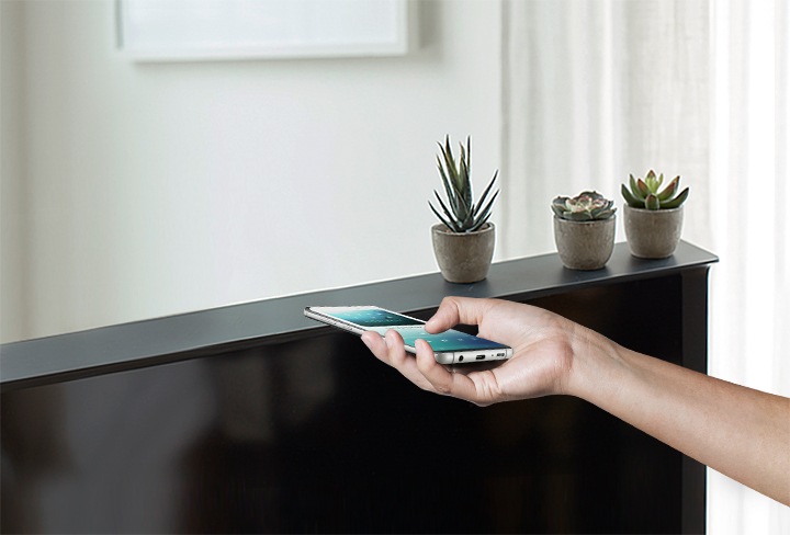 스마트폰을 TV 상단에 올려두고 있습니다.