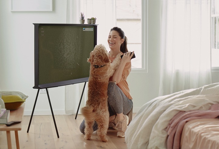 여성과 강아지가  TV앞에 있습니다.