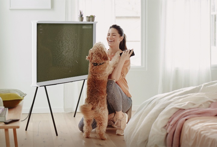 tv앞에서 여성이 강아지와 즐겁게 놀고있는 모습입니다.