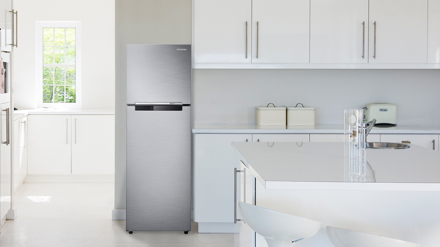 화이트톤 주방 인테리어컷 입니다. 좌측으로는 오픈된 공간에 작은 창문과 하얀색 수납장이 있습니다. 우측은 싱크대와 아일랜드 식탁이 있는 인테리어컷으로 엘레강트 이녹스 컬러의 일반 냉장고가 중앙에 놓여있습니다.