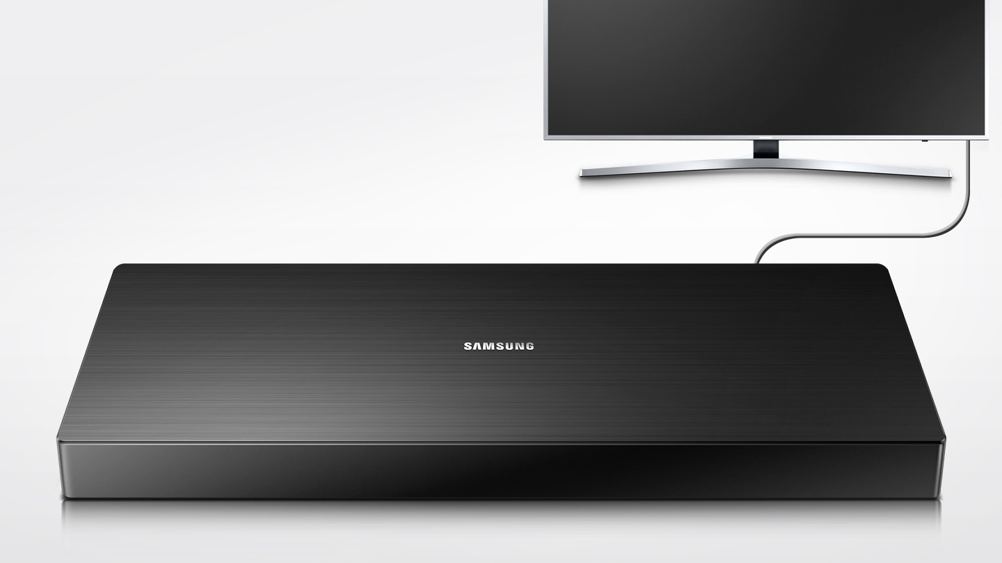 제품이 화면 중앙에 보입니다. 그 뒤로 UHD TV 정면이 보이고 케이블로 함께 연결되어 있는 모습입니다. 