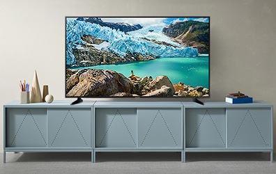 회색 벽을 배경으로 민트색 TV 수납장 위에 빙하와 바다 영상이 보이는 TV 제품이 놓여져 있습니다.