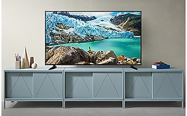 회색 벽을 배경으로 민트색 TV 수납장 위에 빙하와 바다 영상이 보이는 TV 제품이 놓여져 있습니다.