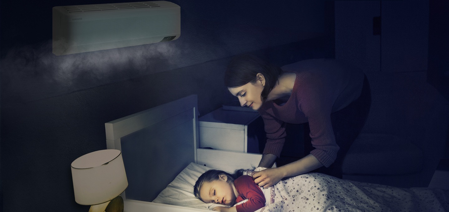 에어컨이 설치된 방에서 여성이 침대에 누워 자고 있는 아이를 바라보는 모습이 보입니다.