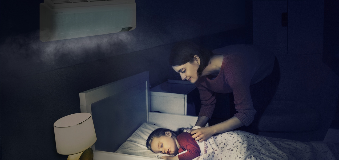 에어컨이 설치된 방에서 여성이 침대에 누워 자고 있는 아이를 바라보는 모습이 보입니다.