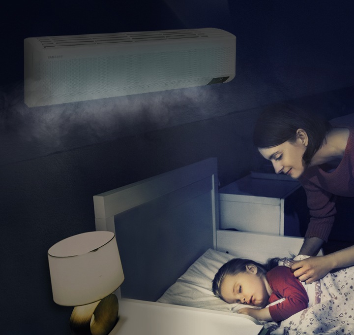 에어컨이 설치된 방에서 여성이 침대에 누워 자고 있는 아이를 바라보는 모습이 보입니다.