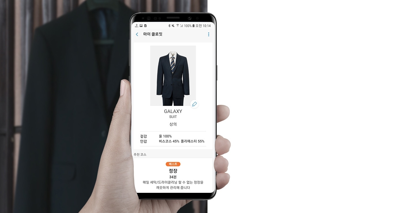 Samsung Galaxy S9 trong tay tôi đang nhìn vào màn hình tủ quần áo của tôi với thông tin về bộ đồ trên màn hình của điện thoại thông minh. Đằng sau điện thoại thông minh là một bộ đồ treo trên móc áo.