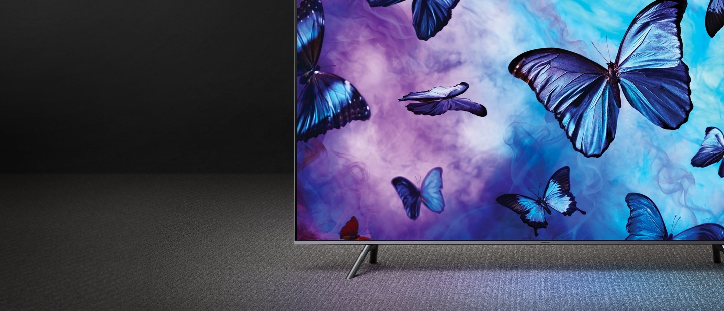 고급스러운 배경 위로 QLED TV가 정면으로 놓여져 있고, 화면 안에는 푸른 색감의 연기 위로 나비들이 날아다닙니다.