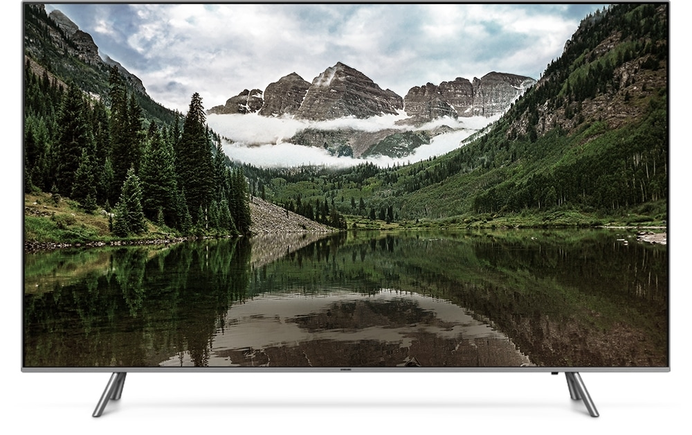 QLED TV 제품이 정면으로 놓여져 있고 화면 안에는 중앙의 호수를 산이 둘러싸고 있는 이미지가 흐리게 보여집니다.
