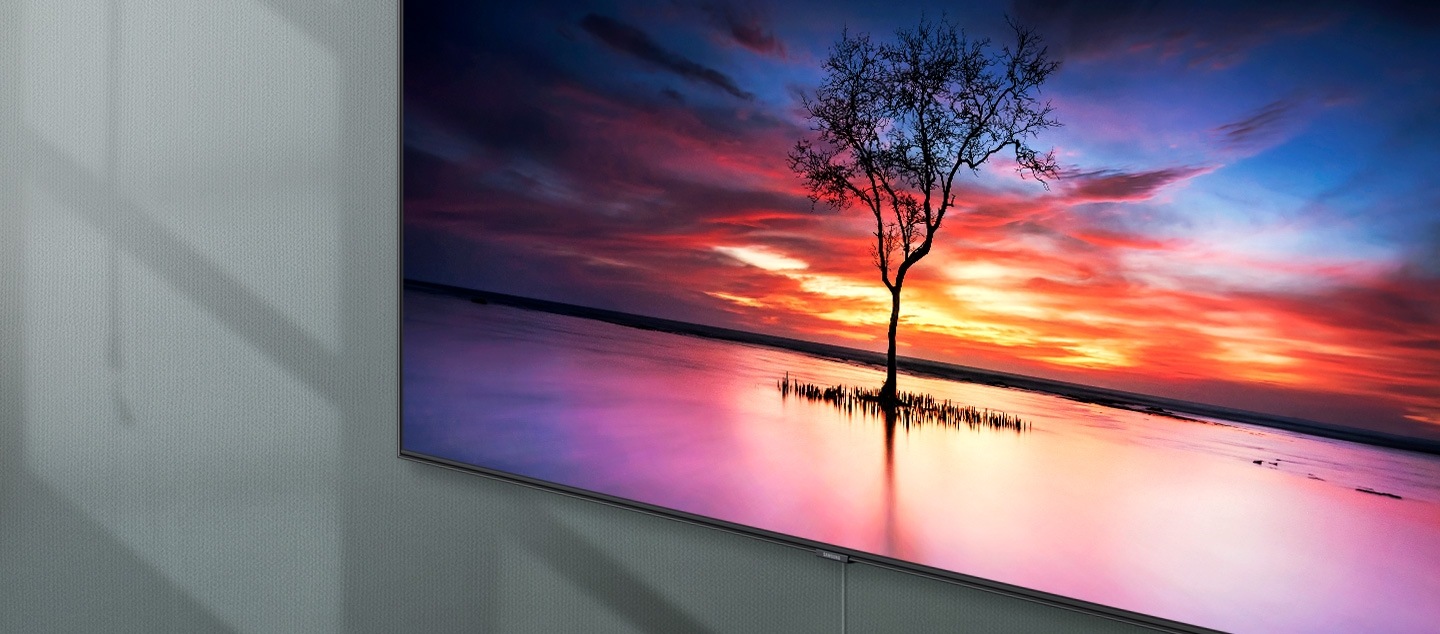 QLED TV 탭 클릭 시 노출되는 이미지 입니다. 벽에 QLED TV가 걸려져 있으며 화면 안에는 얕은 물가 위에 나무 한 그루가 보여집니다. 아침부터 밤까지 화면에 주변 그림자와 인테리어가 비치지 않고 깔끔하게 보여집니다.