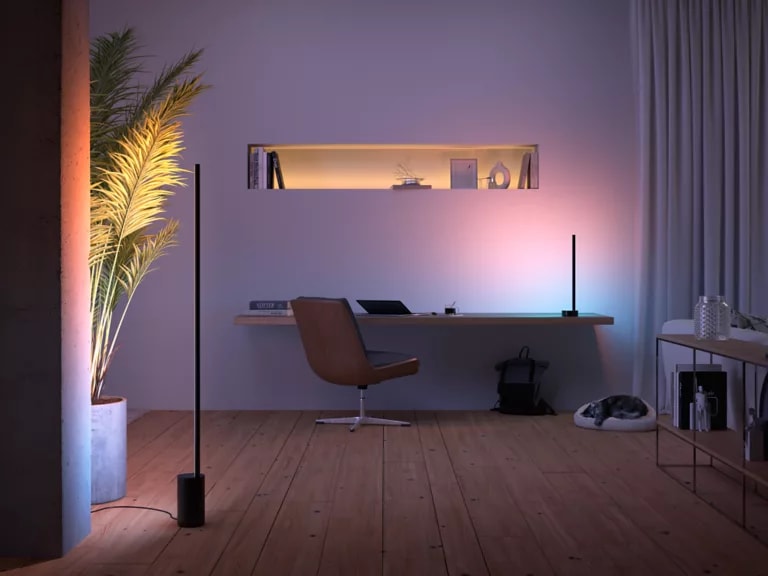 Modern desk and chair with Signe gradient lamps on either side and a cat asleep in a bed on the floor.
