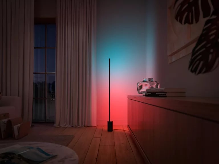 Sideboard and curtained window washed in colorful light from the Signe gradient floor lamp.