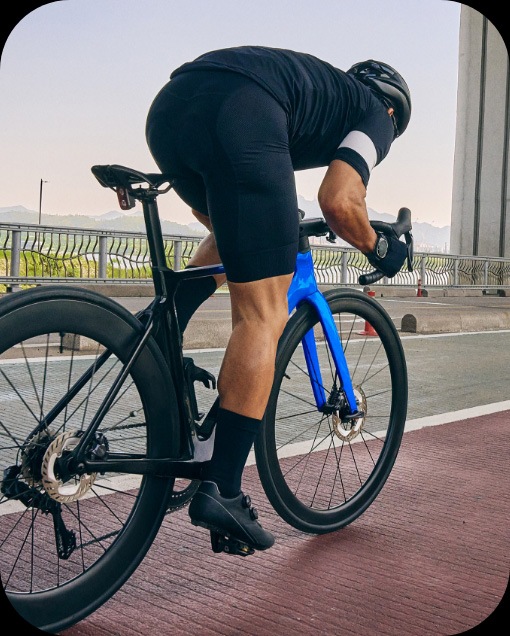 サイクリングウェアを着た男性が、ロードレースバイクでバイクロードを走っている。