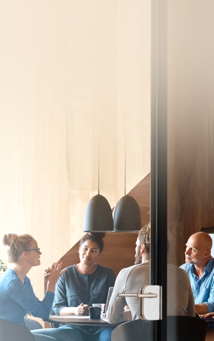 다섯 명의 사람이 테이블에 둘러 앉아 회의를 하고 있습니다. 