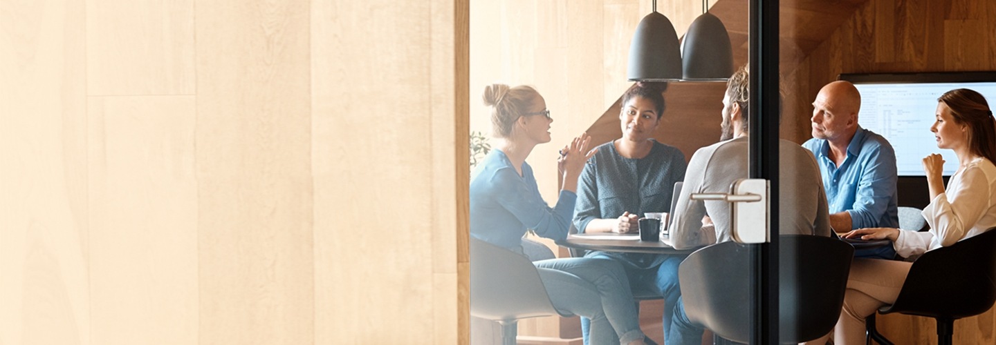 다섯 명의 사람이 테이블에 둘러 앉아 회의를 하고 있습니다. 