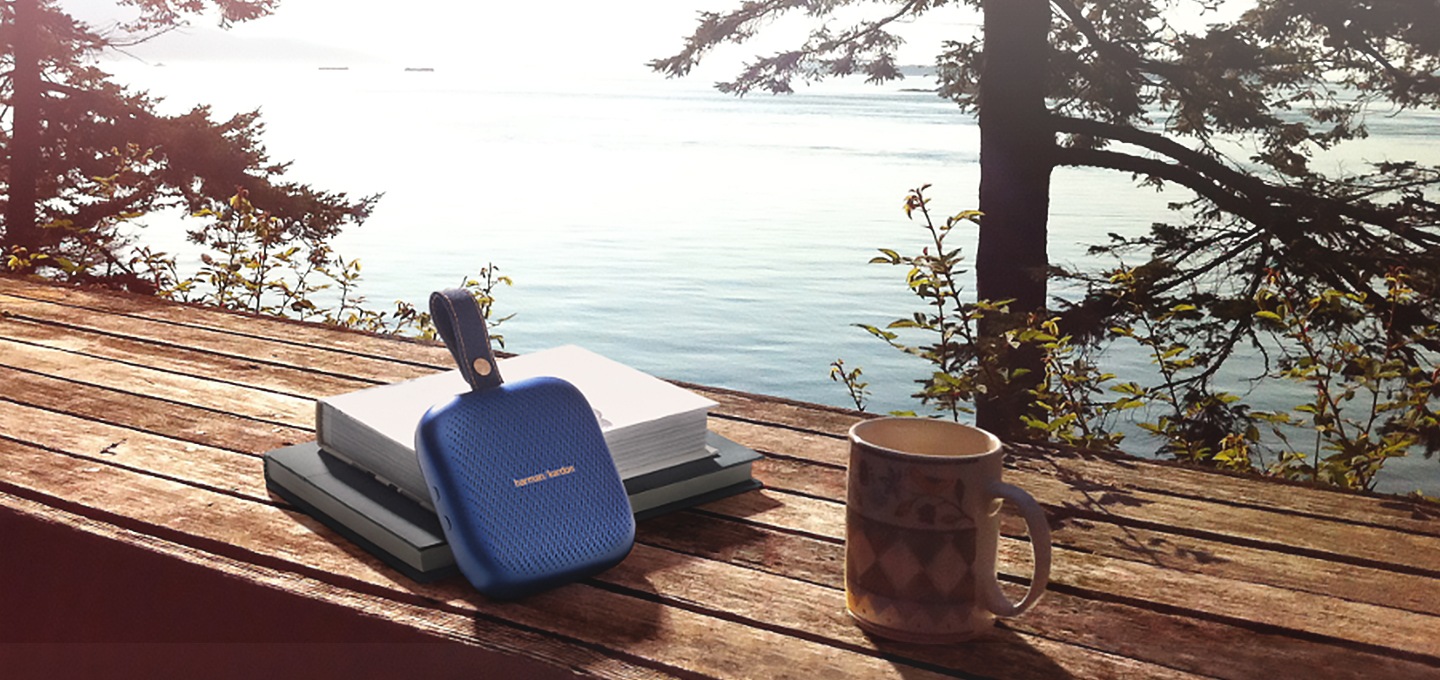 탁자위에 책과 컵, 하만카돈 neo 제품이 올려져있습니다.