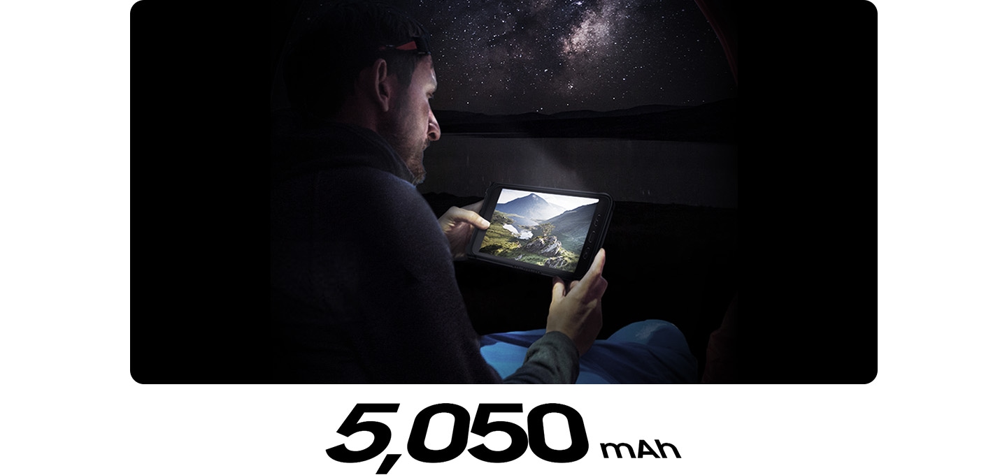 한 남성이 어두운 밤 하늘 아래에서 갤럭시 탭 액티브3로 영상을 보고 있습니다. 하단에는 5,050 mAh 배터리 용량이 표기되어있습니다.
