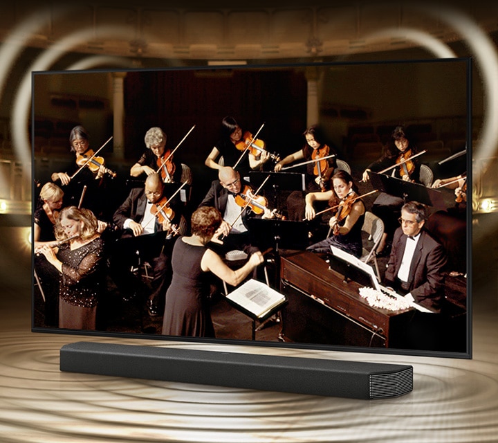 TV 화면 속에 오케스트라 연주하는 화면이 나오고, 사운드바가 보여집니다.