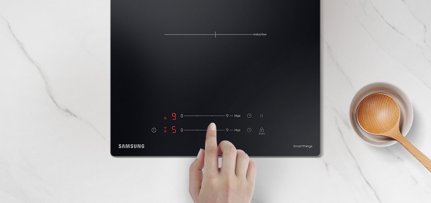빌트인 2구 인덕션 소화구 조작부를 손으로 터치하고 있는 이미지.
