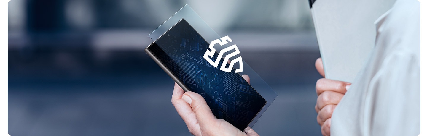 한 사람이 갤럭시 S24 울트라를 손에 쥐고 있습니다. 삼성 녹스 로고가 있는 가상 투명 레이어가 디스플레이 위에 떠 있습니다.