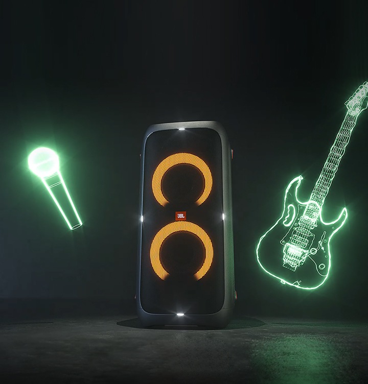 JBL PARTYBOX 310 제품이 세워져있고 뒤로는 기타, 마이크 모양 LED 가 있습니다.