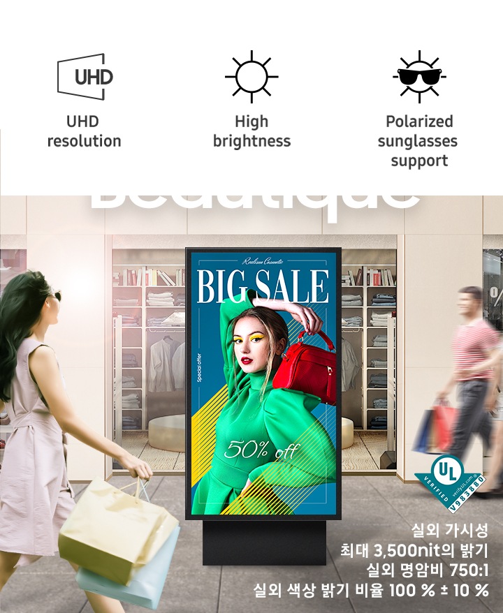 쇼핑백을 들고 걷고 있는 사람들이 있으며 길 중앙에는 선명한 컬러감의 광고가 송출중인 OHA 시리즈가 있습니다. 이미지 우측 하단에는 실외 가시성, 3,500nit 이상의 밝기, 실외 명암비 750:1, 실외 색상 밝기 비율 100 % ± 10 % 라는 텍스트가 있습니다.