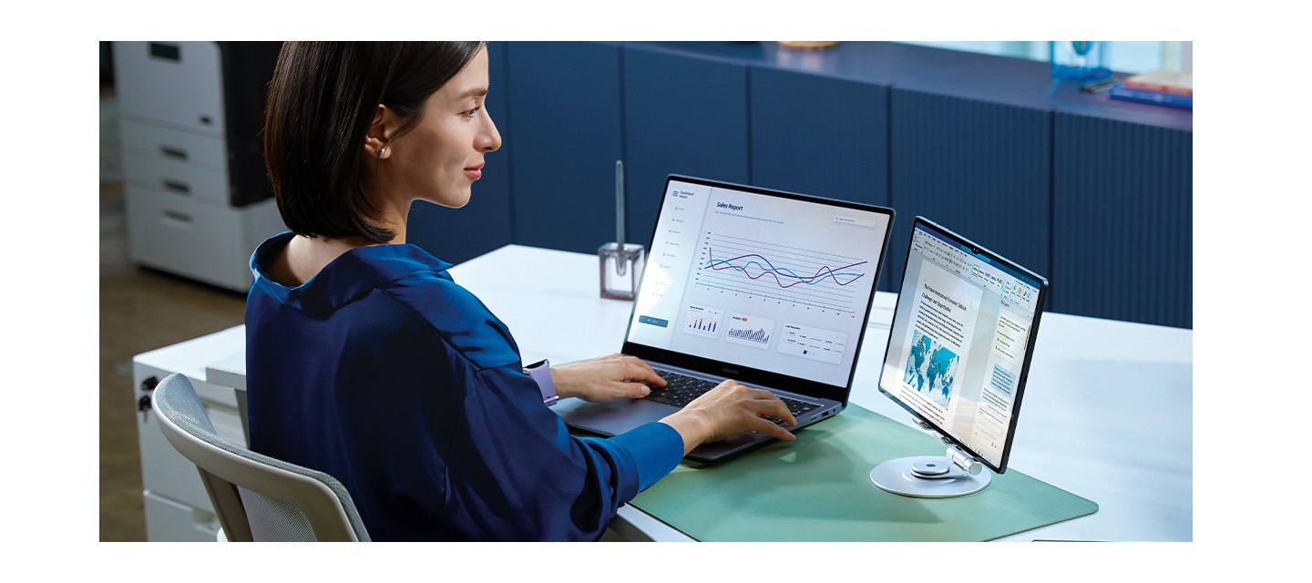 [사무실 공간에서 한 여성이 책상에 갤럭시 북과 보조 모니터를 나란히 두고 작업 중입니다. 두 화면이 연동되어, 더욱 효율적인 작업 흐름을 나타냅니다.]