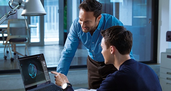 [모던하고 차분한 분위기의 오피스에서 두 남성이 함께 갤럭시 북 앞에서 이야기 나누고 있습니다. 한 명은 책상에 앉아 화면을 가리키고 다른 한 명은 화면으로 몸을 기울이고 있습니다.]