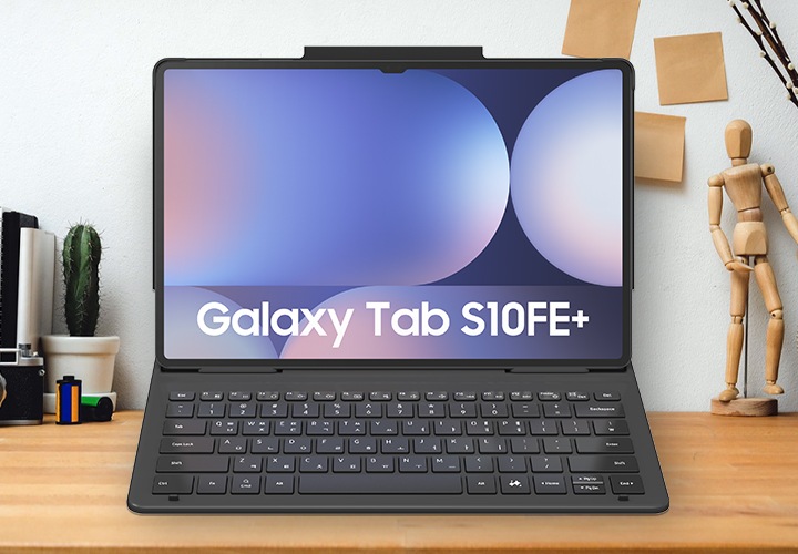 우드톤의 테이블 가운데에 탭이 장착된 커버가 보여지고 있으며, 우측에는 마우스, 좌측에는 다이어리와 스마트폰 등이 놓여져 있습니다.