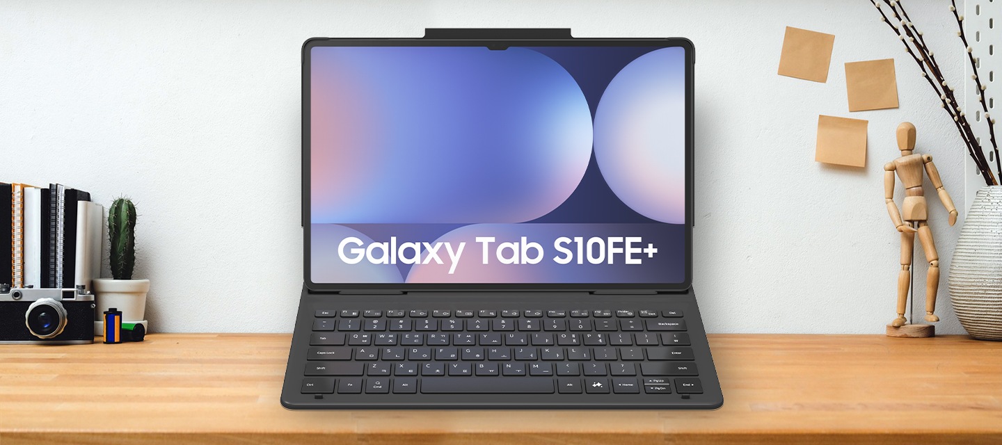 우드톤의 테이블 가운데에 탭이 장착된 커버가 보여지고 있으며, 우측에는 마우스, 좌측에는 다이어리와 스마트폰 등이 놓여져 있습니다.