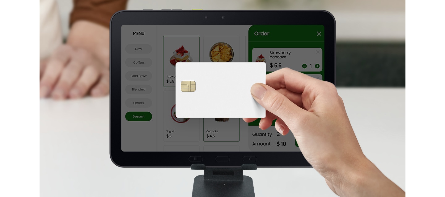 갤럭시 탭 액티브5 프로 화면 근처에서 신용카드를 들고 식당에서 결제를 하고 있는 모습입니다. 갤럭시 탭 액티브5 프로는 메뉴 표시, 주문 접수, 결제 처리에 사용될 수 있음을 알려줍니다.