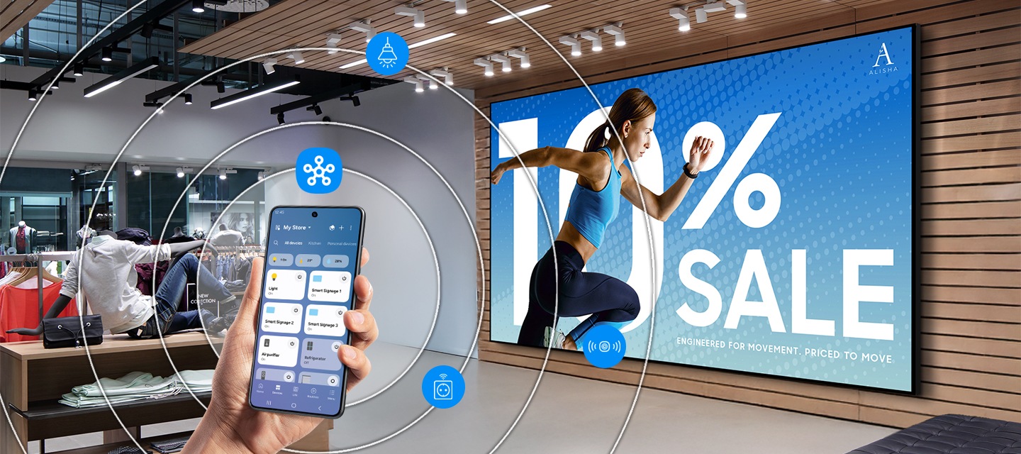 대형 운동복 매장의 벽면에 설치된 단독형 사이니지의 모습이 있고, 좌측에는 스마트폰의 스마트싱스로 화면을 조절하고 있는 손이 보입니다.