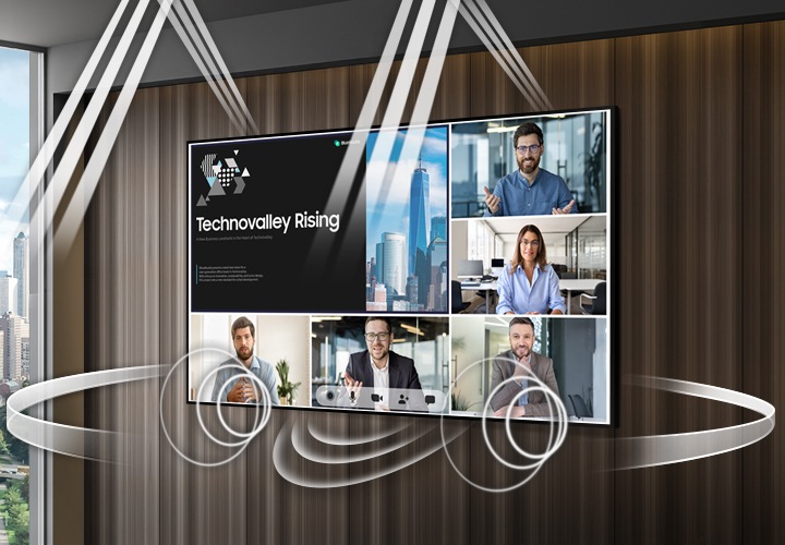회의실 벽면에 대형 단독형 사이니지가 설치되어 있고 화면으로 Technovalley Rising 이라는 자료 화면과 함께 총 5명을 분할하여 줌 회의 중인 화면이 보입니다. 사이니지 하단 중앙, 좌우는 물론, 사이니지 후면에서 앞면으로, 사이니지 상단까지 내장 스피커를 통해 풍부한 사운드가 바오고 있음을 표현하고 있습니다.