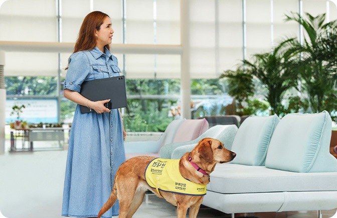 태블릿을 들고 안내견의 리드줄을 잡고 있는 여성의 이미지