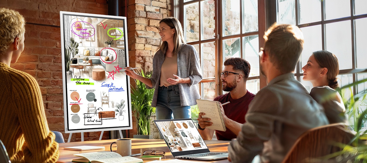 회의가 진행중인 회의실에서 스탠드로 세로모드로 세워진 Flip Pro 전자칠판에 표시하며 프리젠테이션을 진행중인 여성의 모습입니다.