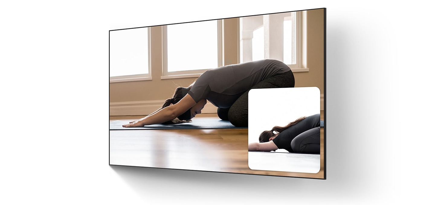 요가 동작 중인 여자 강사의 모습, 강사를 따라하고 있는 여성의 모습이 TV 화면에 두 개의 스크린으로 보입니다.