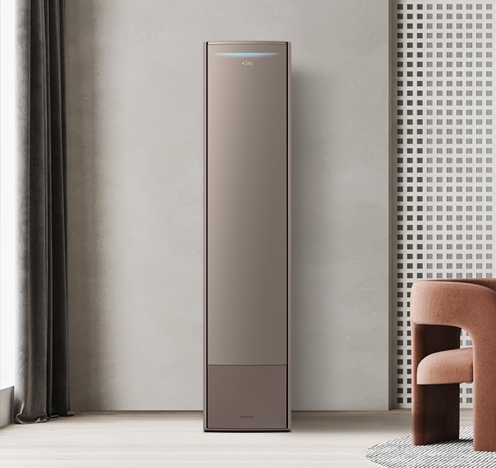 웜그레이톤의 거실의 왼편에 비스포크 무풍에어컨 갤러리가 놓여져 있으며 브라운 메탈 색상의 패널이 설치되어있습니다. 에어컨의 오른편에는 화이트 대리석 벽면이 꾸며져 있고 그 앞으로 붉은 브라운 톤의 1인용 의자와 그레이톤의 벤치형 쇼파가 놓여져 있으며, 앞에는 검은색 컬러의 낮은 테이블 위로 오브제들이 놓여져 있습니다. 