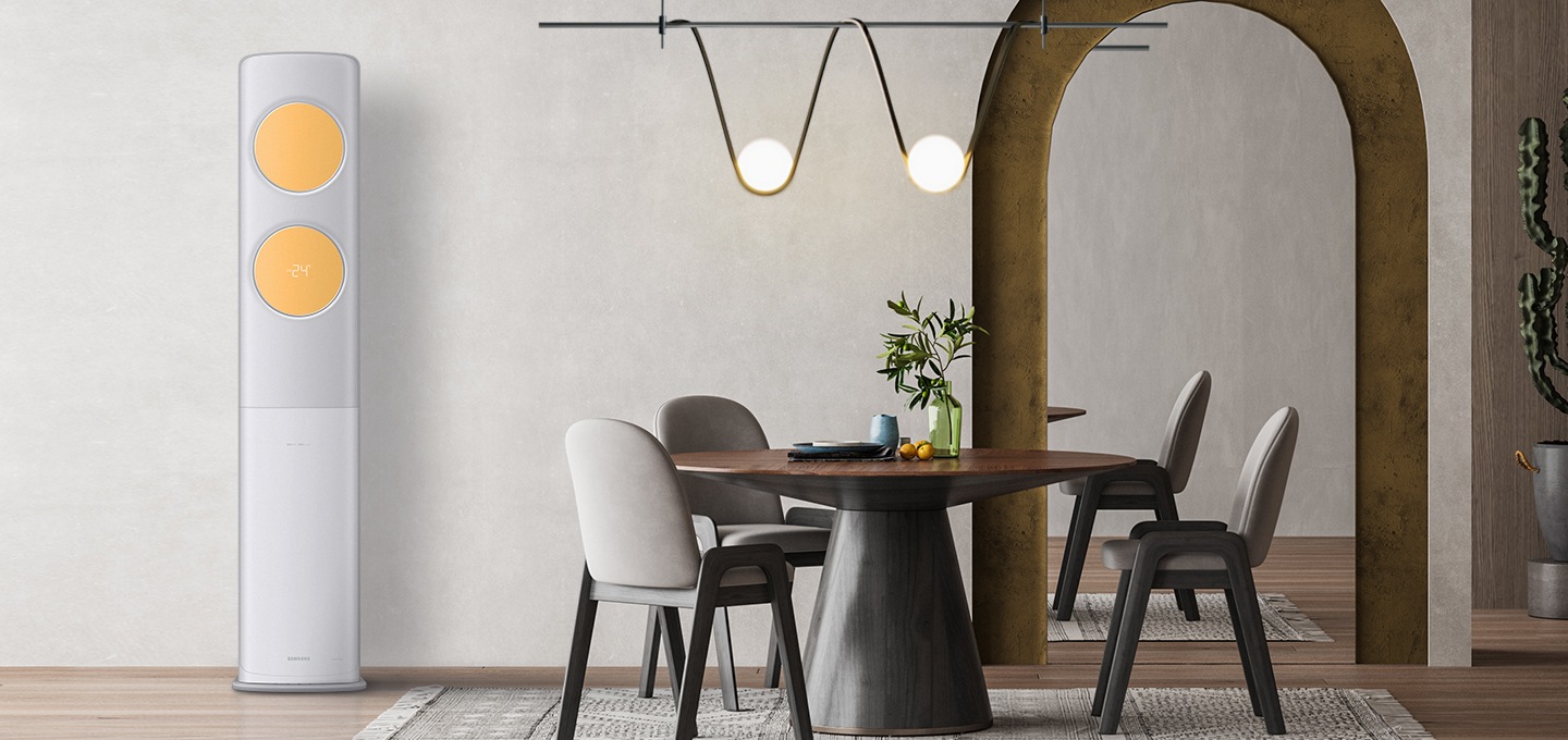 베이지톤의 벽면과 그레이톤의 패브릭이 깔려있는 거실에 짙은 브라운과 그레이 컬러의 3인용 테이블과 의자가 놓여져 있습니다. 테이블의 왼편에 비스포크 무풍에어컨 클래식이 설치되어있습니다. 바람문의 컬러는 밝은 옐로우 컬러이며, 테이블 위에는 모던한 전구, 뒷편에는 아치형의 큰 거울이 테이블의 한쪽 면을 비추고 있습니다. 