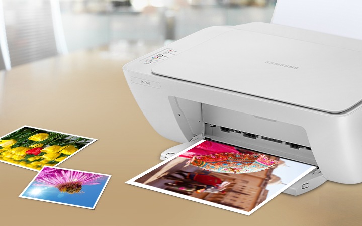 식탁 위에 제품을 오른쪽 위에서 내려본 이미지가 오른쪽 윗부분에 배치하여 있으며 우산을 쓴 사람 사진이 출력 되고 있습니다. 이미지 왼쪽 하단에는 이미 출력된 튤립 사진과 햇빛을 받고 있는 꽃 사진들이 왼쪽 위에서 오른쪽 아래로 나열하여 있습니다.