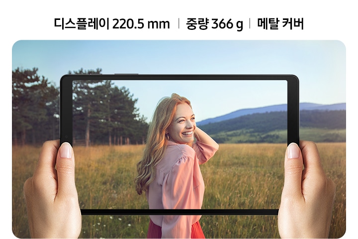 상단에 디스플레이 220.5 mm | 중량 366 g | 메탈 커버 문구가 적혀있고 하단에는 두 손으로 태블릿을 가로로 잡고 들판에 서 있는 한 여성을 촬영하고 있는 모습이 보입니다.