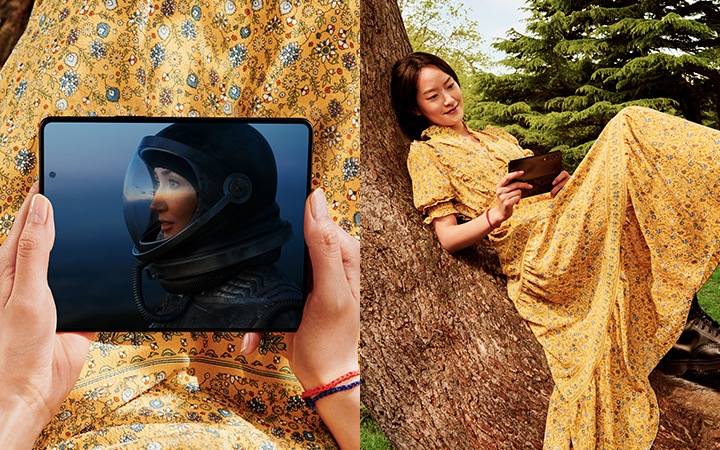 한 여성이 나무 위에 앉아 펼친 상태의 갤럭시 Z 폴드3 5G의 화면을 보고 있습니다.