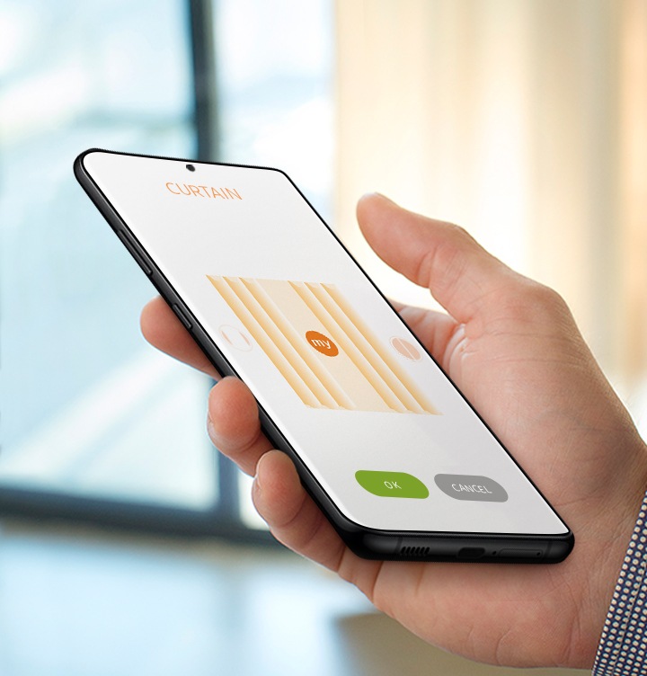 한손으로 핸드폰 화면을 조작하고 있습니다. 커튼을 예약하여 자동오픈 기능을 이용할 수 있습니다.