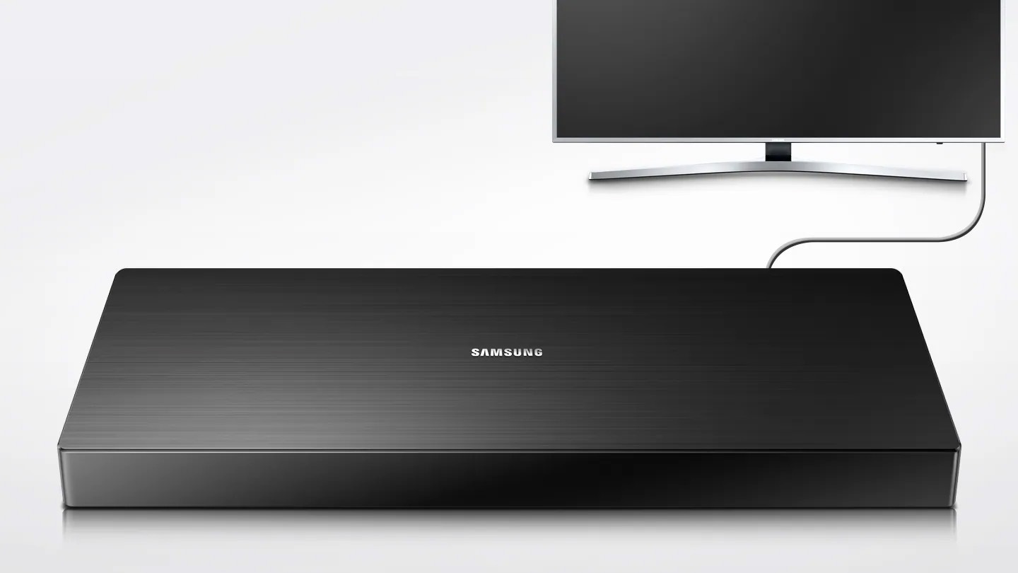 제품이 화면 중앙에 보입니다. 그 뒤로 UHD TV 정면이 보이고 케이블로 함께 연결되어 있는 모습입니다. 