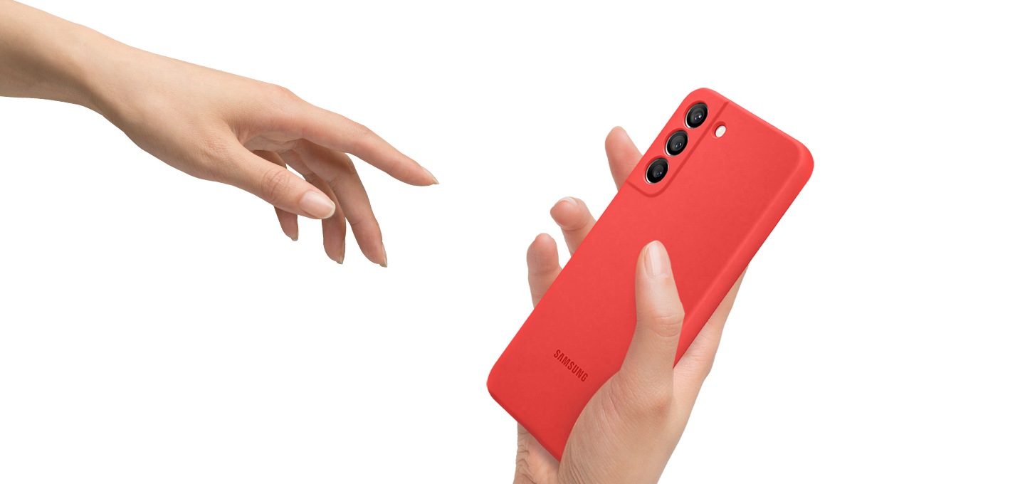 갤럭시 S22+ 실리콘 커버 코랄 색상을 한 손으론 쥐고 있고, 반대손으론 실리콘 커버를 잡기 위해 다가가고 있습니다.