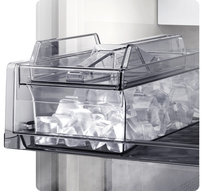 오토 아이스메이커 내상컷이 확대되어 있고 큐브 아이스가 가득 차있습니다. 아이스메이커 상단부에 아이스 스쿱이 놓여있습니다.