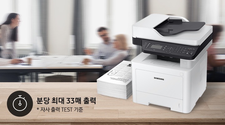 배경에는 바쁘게 회의를 하는 사람들의 모습, 바쁘게 지나가는 사람들의 모습이 흐릿하게 나와 있으며 이미지 오른쪽 부분에는 제품 오른쪽 위에서 내려본 이미지가 배치하여 있고이미지 왼쪽 하단에 분당 최대 40매 출력, 자사 출력 TEST 기준 텍스트가 쓰여 있으며, 타이머 아이콘이 나와있습니다.