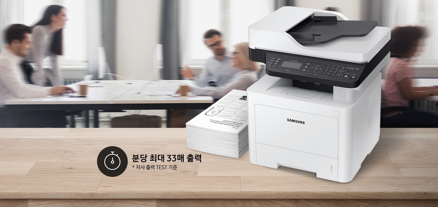 배경에는 바쁘게 회의를 하는 사람들의 모습, 바쁘게 지나가는 사람들의 모습이 흐릿하게 나와 있으며 이미지 오른쪽 부분에는 제품 오른쪽 위에서 내려본 이미지가 배치하여 있고이미지 왼쪽 하단에 분당 최대 40매 출력, 자사 출력 TEST 기준 텍스트가 쓰여 있으며, 타이머 아이콘이 나와있습니다.