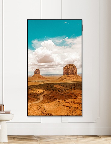 벽걸이 TV가 세로모드로 설치되어있고, 화면에는 붉은 사막 모습이 보입니다.