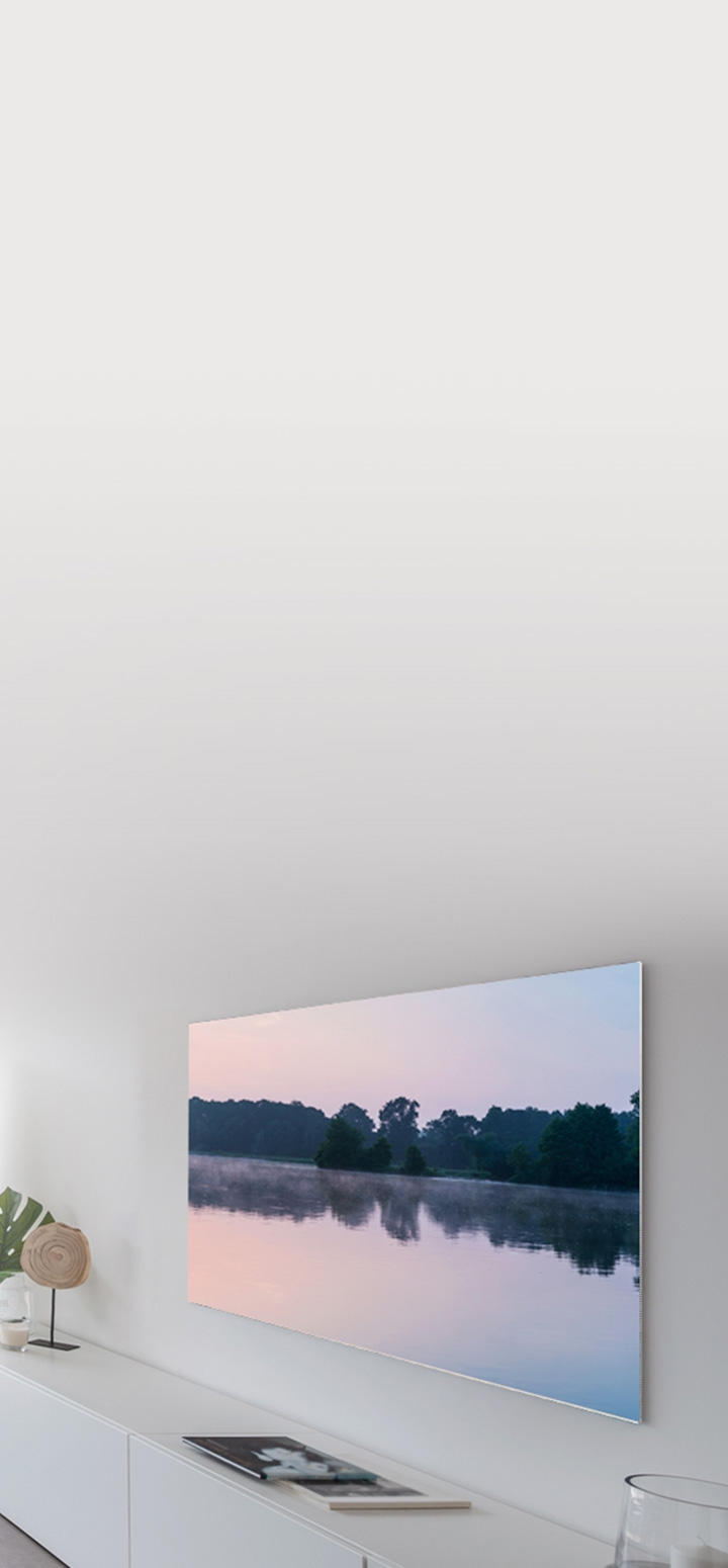 벽면에 TV가 설치되어 있고 TV와 벽면 사이 거리를 최소화 할 수 있음을 나타내는 이미지 입니다. TV온스크린 안에는 노을 풍경의 호수가 보입니다.
